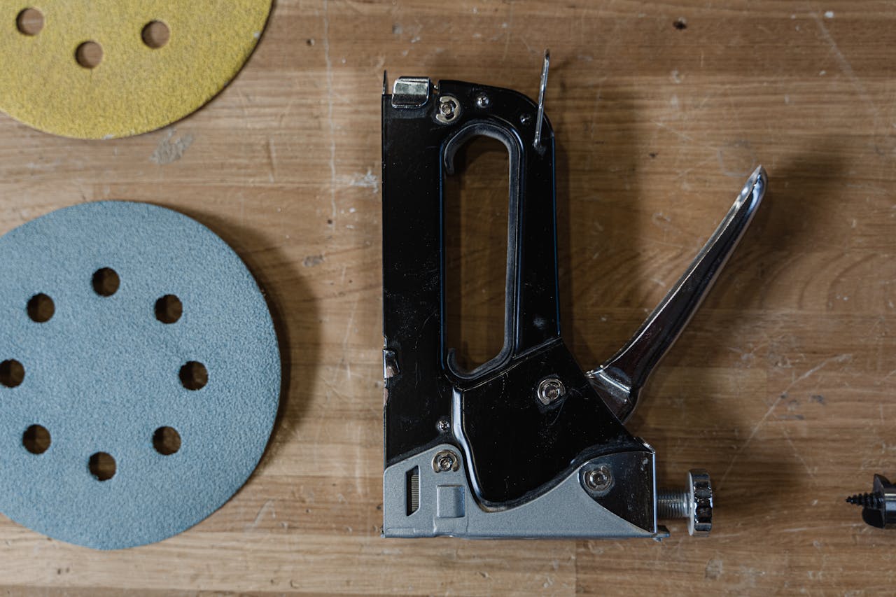 Services Detailed view of a staple gun alongside sanding discs on a wooden table.